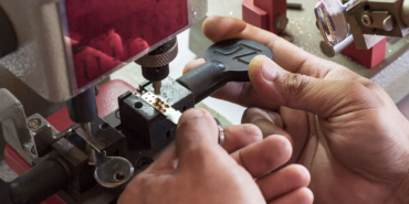Locksmith In Workshop Makes New Key. Professional Making Key In