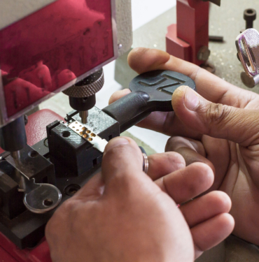 Locksmith In Workshop Makes New Key. Professional Making Key In